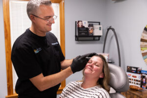Co-founder Ben Kershner skillfully injects Botox near Kitty Hawk into a female BeachGlo Aesthetics patient's forehead. These cosmetic injectable can relax forehead wrinkles to promote a more youthful appearance.