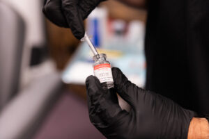 Co-founder Ben Kershner, wearing black gloves and scrubs, prepares a vial of Jouveau, an alternative to Botox for men in Nags Head. These wrinkle relaxers can help men feel powerful and confident.