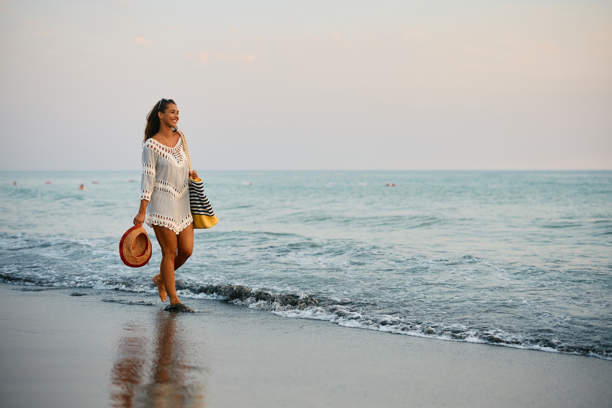 Image of a happy woman walking on the beach after visiting BeachGlo Aesthetics for body contouring in Nags Head.