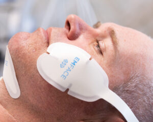 A close up of a male BeachGlo Aesthetics patients wearing the cheek and submentum applicators during Emface near Kitty Hawk.